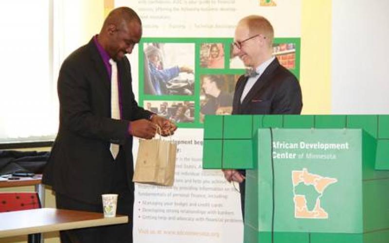 Nasibu Sera presents Jeremy Hanson Willis a thank you gift in a brown bag