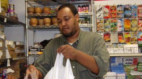 In 2000, Abdiqafar Adan organized seven other partners to start the Afrik grocery store and wholesale operation on Cedar Avenue. Photo of Abdiqafar Adan bagging a customer purchase in his grocery