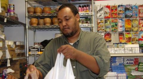 Photo of Abdiqafar Adan bagging a customer purchase in his grocery